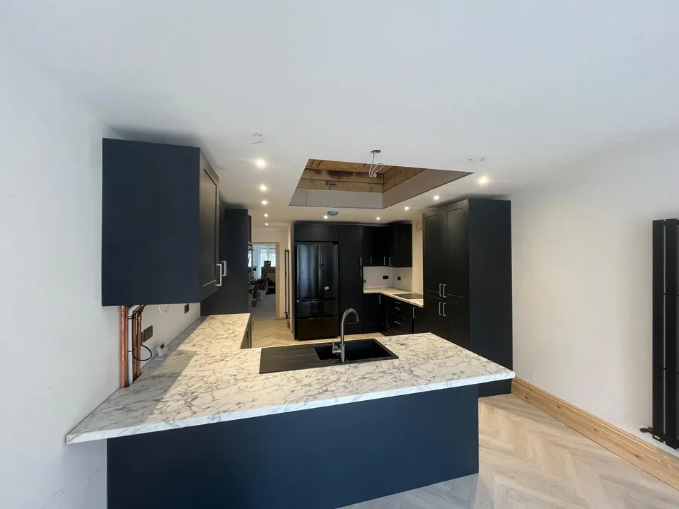 Dark kitchen with a marble-effect worktop peninsula and herringbone floor