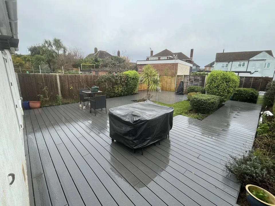 Grey composite decking with lawn, shrubs and covered outdoor furniture