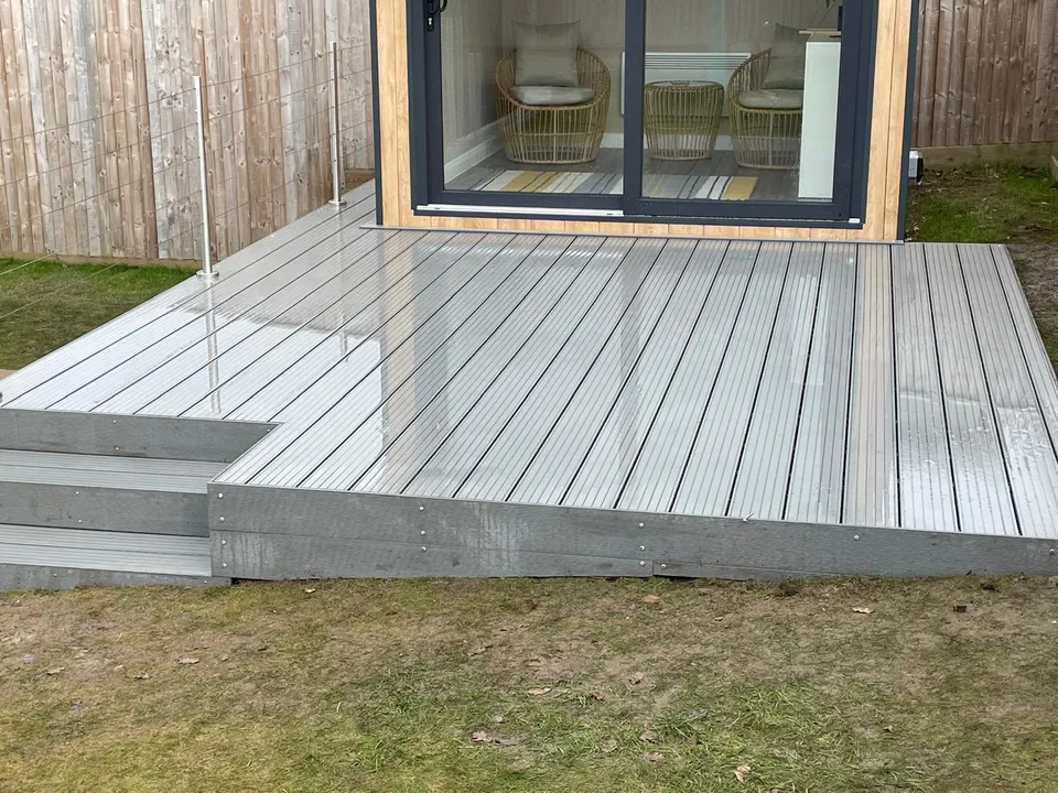 Grey composite decking with a step in front of a garden room