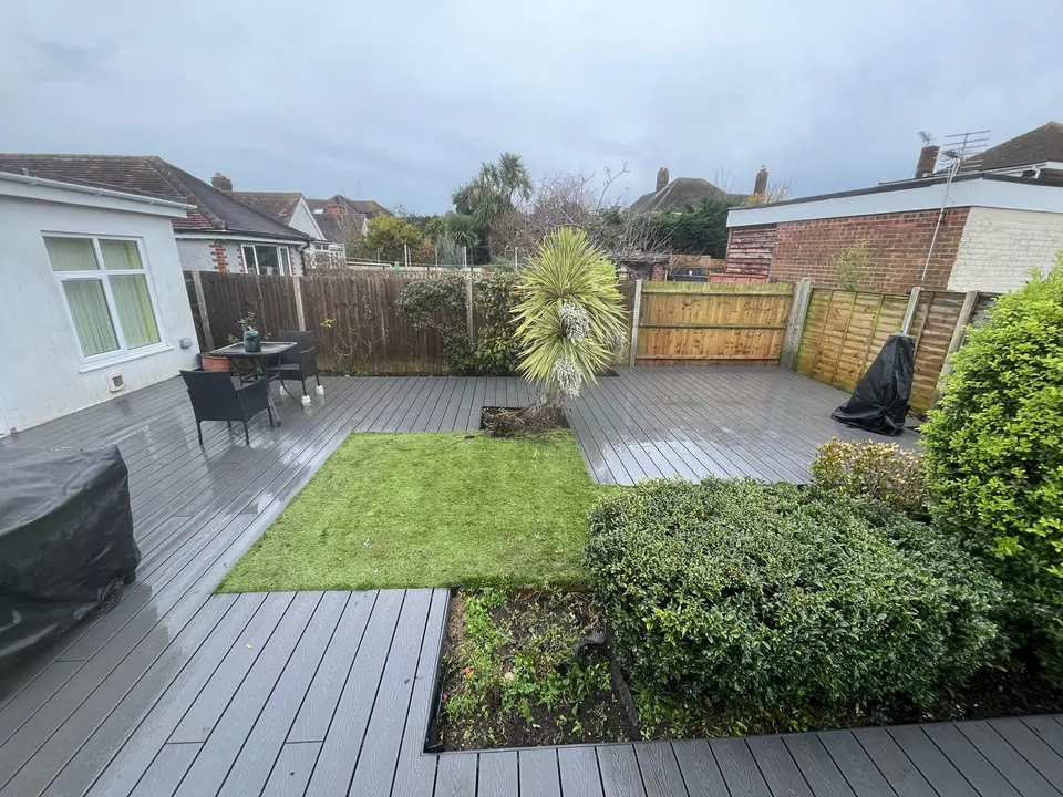 Finished garden with grey composite decking, lawn and evergreen shrubs
