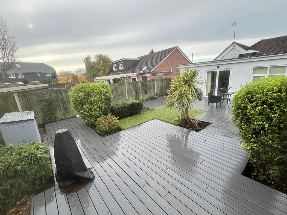 Grey composite decking with planted borders, seen from the house